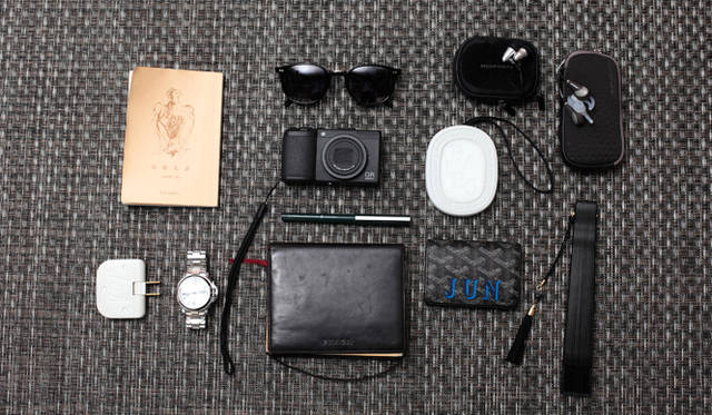 谷川氏に披露して頂いた、旅に“同行する”モノをまとめて撮影。左上から時計回りに、ボーズのヘッドフォン「クワイアットコンフォート」、宮脇賣扇庵（みやわきばいせんあん）の扇子、ゴヤールの名刺入れ、無印良品の「再生紙ノート・無地 A6」、オフィチーネ パネライの「ルミノール」、タップ、谷崎潤一郎の随筆『陰翳礼讃（いんえいらいさん）』、英ロンドンのアイウェアブランド「カトラー＆グロス」のサングラス、マランツのインイヤーヘッドフォン「HP101」、「diptyque（ディプティック）」のルームフレグランス、クラフトデザインテクノロジーの「Plastic Fauntain Pen」、リコーのコンパクトデジタルカメラ「GR」