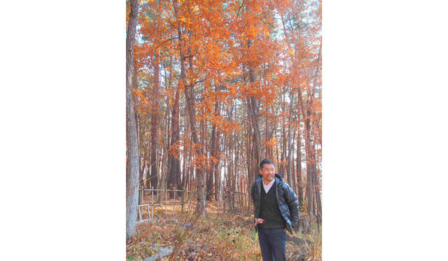 <strong>特集｜「パーマカルチャーデザイン」を暮らしのなかに</strong>　紅葉が美しい広葉樹の林の前で。林の奥には小麦畑があるという