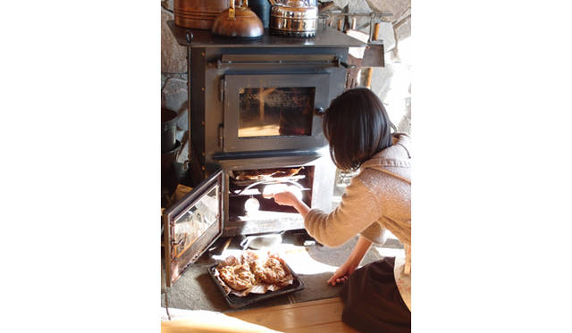 <strong>特集｜「パーマカルチャーデザイン」を暮らしのなかに</strong>　奥様の千里さんは、薪ストーブでチキンをグリル