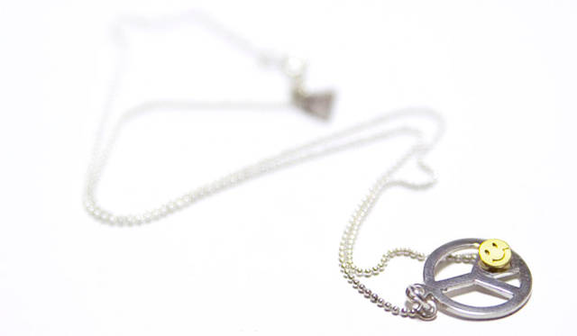 <strong>BLIND MAN TOGS｜ブラインド マン トグス</strong>　ビンテージ・シルバー製スプーンのすくう部分からハンドメイドにて「ピースマーク」を切り出し、さらにスマイル（18K）をチェーンの先端にセットしたネックレス。B.M.T SPOON NECKLACE「PEACE & SMILE」1万9740円
