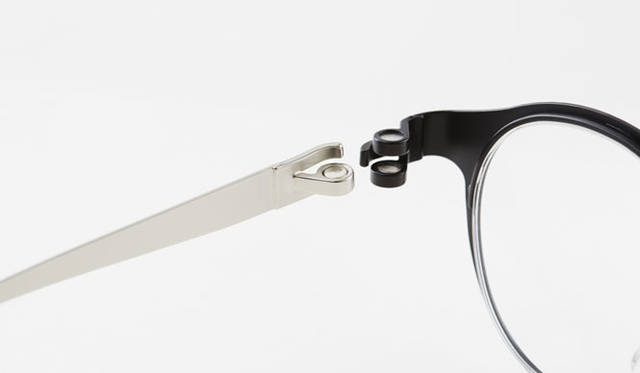 <strong>「magne-hinge for by｜n」</strong><br />ヒンジ部分をネジではなく「磁石」で止めることで、ユルんだり破損する心配が少なく、手軽にテンプル（つる）が着脱できるメガネ。フレームは0.8mm厚のチタンを切り出して作成し、巻き付くように磁石が固定されている。ふたつの磁石の間にもうひとつの磁石を挟むように配置することで、反発力と誘引力のどちらも使って固定をしながら、メガネを折り畳む際の回転も可能。横方向に引っ張ると簡単にテンプルを取り外せるため、一つのフロント（レンズ＋枠）に対して異なる色や素材のテンプルを複数購入することで、自由に組み合わせて楽しめるようになった。