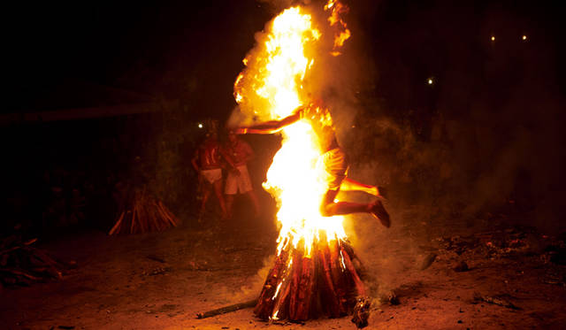 トランス状態になった男性が燃え盛る薪の束を飛び越える。ベネズエラ北部でおこなわれた儀式の一幕。 © Kitra Cahana/National Geographic