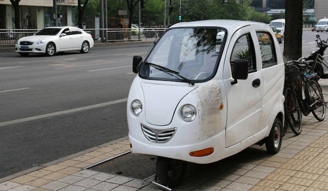 キャビン付き3輪バイクの向こうをインフィニティが通過する。北京のメルティングポット的自動車体系を象徴する風景