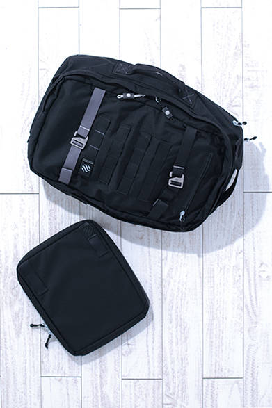 ショルダーハーネスを背面ポケットに収納すれば、ブリーフケースとしても使えるデイパック。iPadが収納できる大きめのポーチは、おなじシリーズのバッグに取り付け可能だ。「MONOLITH DAY PACK」［H38×W29×D15cm（22L）］3万3000円、「DETOUCHABLE POUCH L」［H27×24×5cm］7800円（ともにHeimplanet）<br />※すべて税抜き価格