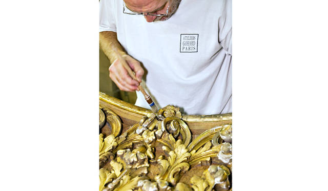アトリエ・ゴアールの職人が、ル・クレベール・バーの木部の金箔仕上げを施しているところ