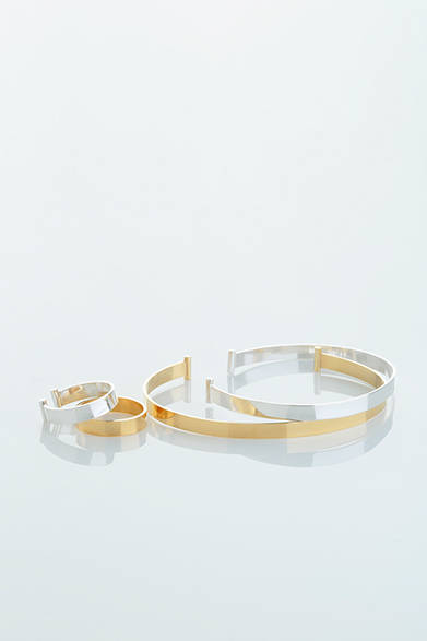 WOMENS｜シルバーとゴールドメッキ、それぞれ薄いプレートから生まれたシャープなフォルムから、女性らしさと強さが感じられるデザイン。留め部分には円柱のようなデザインがあしらわれている。リングはシルバーとゴールドのペア。「プレートブレス ゴールド」4万2000円、「プレートブレス シルバー」3万1000円、「プレートペアリング」3万9000円（すべてアデリン カシュー）<br />※すべて税抜き価格