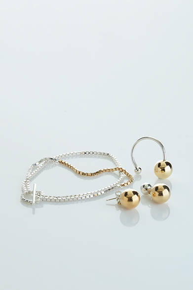 WOMENS｜ゴールドとシルバーのコンビネーションが美しい作品。リングは留め具の球体がユニーク。また、ピアスはゴールドの球体が揺れるキュートな仕様に。チェーンブレスは2連になっており、シンプルながらゴージャスさもある。「ゴールド×シルバー リング」3万円、「ゴールド×シルバー ピアス」4万3000円、「ゴールド×シルバー チェーンブレスレット」2万1000円（すべてアデリン カシュー）<br />※すべて税抜き価格