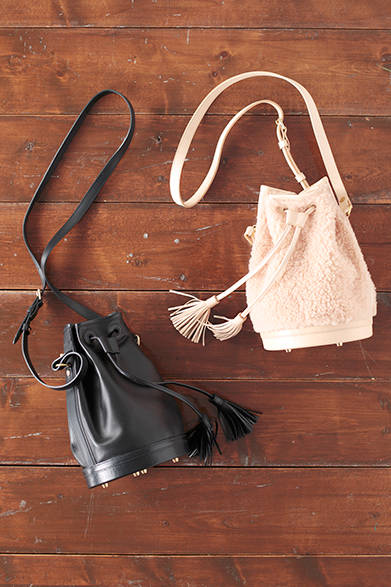 WOMENS｜肌触りが良く、モコモコとした風合いも愛らしいピンクのムートンと、しっとりとしたやわらかさと、なめらかな質感をもつブラックレザーの巾着バッグ。カジュアルなデザインながら、パリにあるオートクチュールのファクトリーで製作されているためか、ラグジュアリーなムードも漂う。左から、「ムートン巾着」13万円、「レザーソリッド巾着」12万6000円（ともにフォースティン パリ）<br />※ともに税抜価格