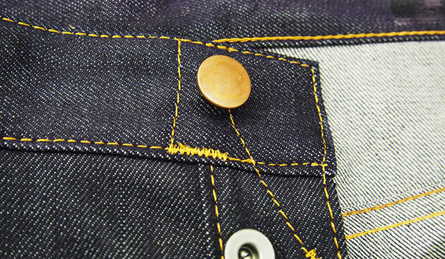 純銅のフロントボタンには、コットンフラワーのマークが入る。使っていくほどに、浮かび上がってくる仕様