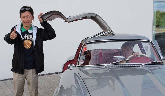 1959年生まれ　自動車雑誌編集者からレーシングドライバーのすキルを持つモータージャーナリストを目指して独立。編集部時代に始めたレースも本格化して、グループA、N1ツーリングカー耐久レースではシリーズチャンピオンを獲得。近年は自動車開発の聖地とされるドイツ、ニュルブルクリンク24時間レースにアストンマーティン・ワークスチームから出場すること４回、2度のクラス優勝を飾りチームから信頼を得る。　日本自動車ジャーナリスト協会会員、日本カーオブザイヤー、ワールドカーオブザイヤー選考委員。<br />写真のなか、左手を添えたガルウィングは、試乗会場に展示されていた「300 SL」