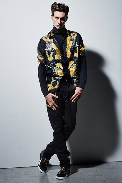 <strong>VERSACE（ヴェルサーチ）</strong>　バイクにまたがる現代のカウボーイをイメージしたスタイリング。クルマやバイクなどのイメージとアイコニックなVersaceのモチーフや装飾品をコラージュしたシャツの新柄プリントに注目。<br />シャツ19万6560円、セーター9万5040円、デニムパンツ7万5600円、チェーン付ウォレット6万8040円、シューズ19万9800円（ヴェルサーチ／阪急メンズ東京2階）