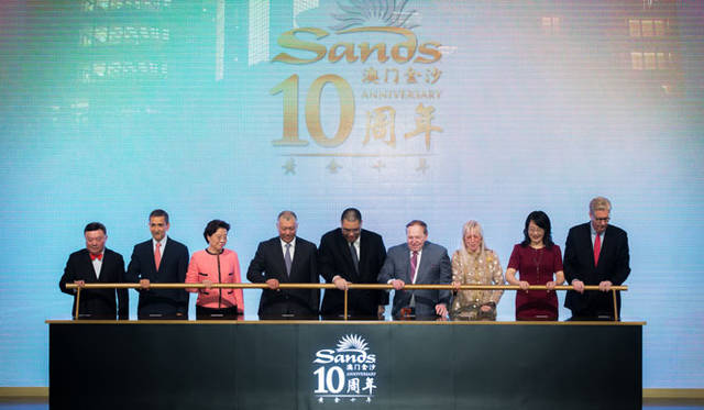 <strong>カジノ・リゾート「サンズ・マカオ」10周年</strong>　左から右へ、ヴェネチアン・マカオ社マネージング・ディレクターAntonio Ferreira氏、MSARエグゼクティブ・カウンシル兼立法議会のLeonel Alberto Alves氏、中央人民政府駐マカオ特別行政区連絡執行室の副館長Qui Hong氏、中国人民政治協商会議副議長Edmund Ho Hau Wah氏、マカオ　S.A.Rのチーフ・エグゼクティブであるFernando Chui Sai On氏、ラスベガス・サンズ社取締役会長兼ディレクター及びチーフ・エグゼクティブ・オフィサーのSheldon Adelson氏とMiriam Adelson博士、中華人民共和国外交部駐香港特別行政区特派員公署のHuang Xing Qian氏、サンズ・チャイナ社社長兼CEOのEdward Tracy氏がセレモニーを執り仕切った