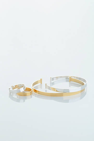 WOMENS｜シルバーとゴールドメッキ、それぞれ薄いプレートから生まれたシャープなフォルムから、女性らしさと強さが感じられるデザイン。留め部分には円柱のようなデザインがあしらわれている。リングはシルバーとゴールドのペア。「プレートブレス ゴールド」4万2000円、「プレートブレス シルバー」3万1000円、「プレートペアリング」3万9000円（すべてアデリン カシュー）<br />※すべて税抜き価格