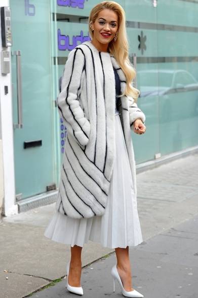 <strong>Rita Ora｜リタ・オラ</strong><br /><br />ロンドンの街に現れた歌手のリタ・オラ。真っ白のロングプリーツスカートに、フェンディのファーコート、さらにホワイトのパンプスを揃えた、オールホワイトの着こなし。パール付きのイヤーカフとレッドリップでアクセントを効かせた。