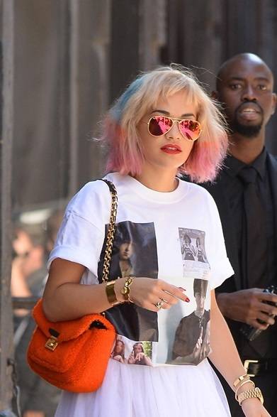 <strong>Rita Ora｜リタ・オラ</strong><br /><br />ニューヨークの街角でキャッチしたリタ・オラ。プリントTシャツと白いスカートのシンプルなカジュアルスタイルに、サングラスとバッグ、そしてユニークなヘアを鮮やかなアクセントを加える。