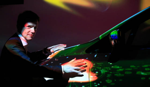 “触れる”プロジェクションマッピングのデモンストレーションをおこなうデュポン氏。手元の赤い光が触れた奇跡を描く