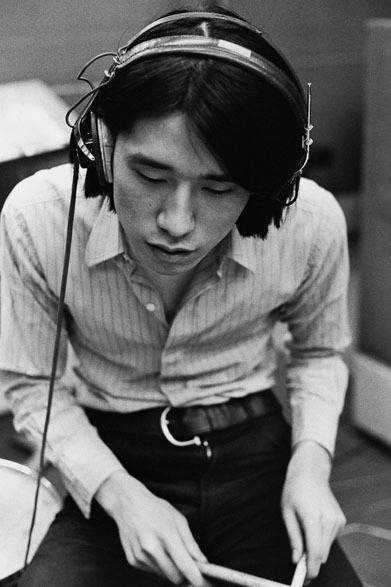 <strong>写真集アプリ「野上眞宏のSNAPSHOT DIARY」</strong>　1970年4月 　日本のロックにとって記念すべきアルバムとなった『はっぴいえんど』（発売は、1970年8月）の制作にあたって、メンバーたちは、まず自分の思っているロックミュージックの探究、それに日本語をのせるというチャレンジ、全曲オリジナルということにこだわったのはもちろんであるが、もう一つ録音そのものの質を高めることにも熱心だった。<br>細野はエイプリル・フールの録音のずっと以前から、本場アメリカのレコーディングに比べて劣っている日本の録音に不満を抱いていた。素人のぼくにも理解できる範囲で言うと、ヴォーカルの音が前に出すぎて歌と演奏との一体感がない、ドラムの音が軽すぎて心に訴えるズシンとした感じがないなどがあった。欧米録音のロックと歌謡曲中心の日本のレコードのサウンドの違いは明白であった。　© Mike Nogami