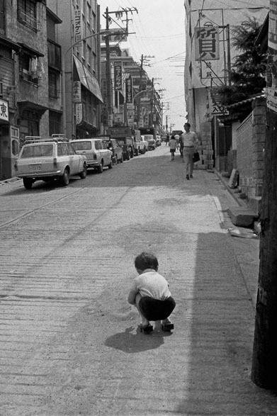 <strong>写真集アプリ「野上眞宏のSNAPSHOT DIARY」</strong>　1971年9月　下駄を履いた子ども。　© Mike Nogami