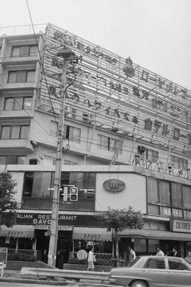 <strong>写真集アプリ「野上眞宏のSNAPSHOT DIARY」</strong>　1971年10月　セントラルアパートの明治通り側の外観写真。原宿の表参道と明治通りの角、今は「東急プラザ 表参道原宿」のある所にセントラルアパートはあった。コープオリンピア、山手教会とともに、70年代初頭の原宿の象徴だった。地下鉄もまだなく竹下通りもただの裏通りだったし、原宿は人通りの少ない静かな街だった。セントラルアパートのきちんとした写真が現存していないようなので、この写真をもっとまじめに撮っておけばよかったなぁと反省！　© Mike Nogami