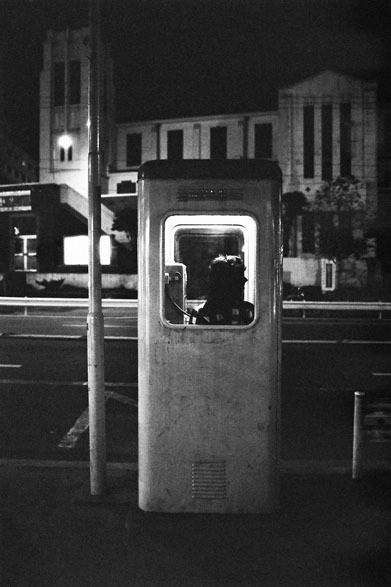 <strong>写真集アプリ「野上眞宏のSNAPSHOT DIARY」</strong>　1971年11月　原宿、表参道。夜の街を一人で歩くのは好きだ。手で耳をふさぐと夜の都会の美しさが際だってくる。夜の写真はたくさん撮った。当時でも珍しくなりつつあった旧型電話ボックス。背景は山手教会で、細野が結婚式を挙げた場所。今はラフォーレ原宿が、この跡地に建っている。　© Mike Nogami