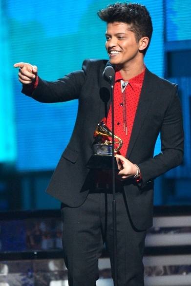 <strong>Bruno Mars｜ブルーノ・マーズ</strong><br /><br />最優秀ポップ・ヴォーカル・アルバム賞に選ばれたブルーノ・マーズ。シンプルなサンローランのブラックスーツに、ドットの赤いシャツとポロタイで遊び心のあるスタイリングに。Courtesy of Saint Laurent