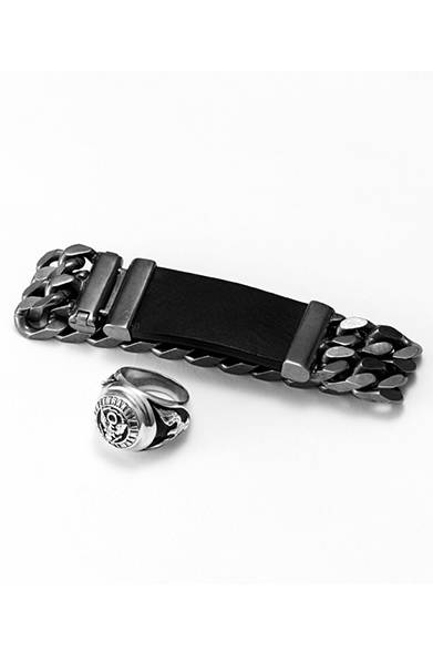 レザーとチェーンのコンビ使いでつくられたブレスレットは、メタル部分が渋めの風合いに加工されたシックなデザイン。ボリュームのあるリングは、凹凸部分に黒のペイントを施すことで、より精悍なイメージへと仕上がっている。ブレスレット2万6000円、リング2万2000円（ともにディーゼル ブラック ゴールド）