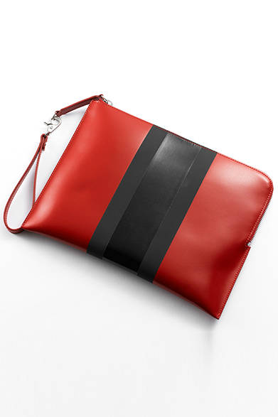 <strong>WOMENS｜</strong>いまや定番となりつつある、クラッチバッグはインパクトのある赤をセレクト。センターには今季のキーカラーのひとつである、艶感のある黒とマットな黒をライン使いすることで、ブランドのアイデンティティを主張している。[W31×H22×D2cm]、バッグ6万1560円（ディーゼル ブラック ゴールド）