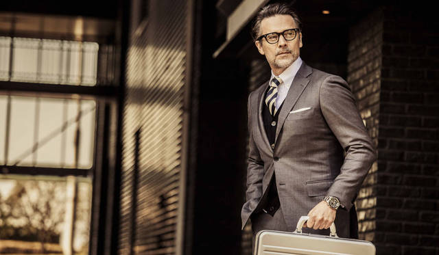 鉄板のビジネススタイルとも言えるグレースーツ。きっちりとした装いにも、トランスオーシャンはよく似合う。スーツ価格7万9920円(シップス銀座店Tel.03-3564-5547)、シャツ価格2万1600円／ギ ローバー、ネクタイ価格1万9440円／ルイジ ボレッリ（すべてシップス銀座店Tel.03-3564-5547）、カーディガン価格2万8080円／ルトロワ（八木通商Tel.03-6809-2183）、メガネ価格2万9160円／モスコット（モスコット トウキョウTel.03-6434-1070）、その他スタイリスト私物。