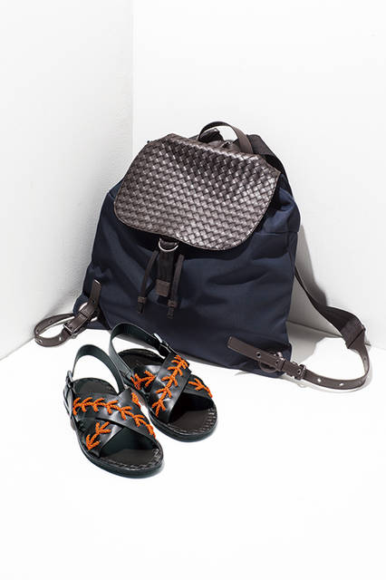 アイコンであるイントレチャートをフラップ部分に、そしてボディーにはネイビーの軽量なナイロンを使った異素材ミックスのバックパック。クロスレザーストラップに蛍光色の丸紐が編み込まれたサンダルは、インソールにイントレチャートの刻印が施されている。<br><br>バッグ[W45×H43cm]29万7000円、サンダル7万4520円／ボッテガ・ヴェネタ〈阪急メンズ大阪2階〉〈阪急メンズ東京1階〉