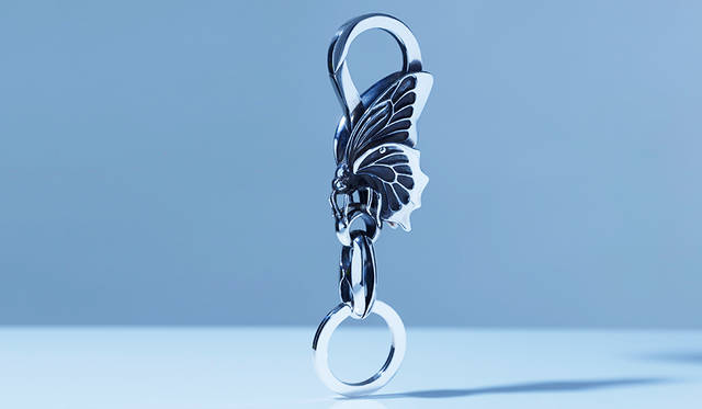 フック部分にバタフライ（蝶）の彫刻が施されたシルバー製のキーリング。使用するにつれて重厚で味わ深い、アンティーク調の風合いになるのも魅力。<br /> <strong>「スロープキーリング　バタフライ」</strong><br /> 価格7万円（税抜）