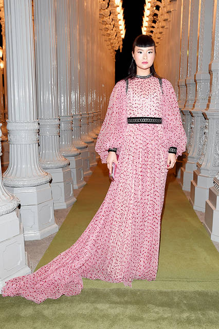 <strong>エイジア・チャウ</strong><br />ドレス：2016-2017年秋冬コレクションのタイガーパッチとクリスタルトリム、パールトリムがあしらわれたペールピンク メタリックフューシャドットチュール ロングスリーブドレス<br />バッグ：クリスタル タイガーヘッドクロージャー付きピンクメタリックレザー クラッチ<br />シューズ：シルバーとブラックレザーのプラットフォーム サンダル