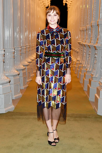 <strong>マケンジー・リー</strong><br /> ドレス：2017年クルーズ コレクション ルック84のスパンコール刺繍のウェブ ボウがあしらわれたマルチカラー総刺繍ロングスリーブ チュールドレス<br /> バッグ：パープルサテン ボックスクラッチ<br /> シューズ：ブラックレザー ハイヒールサンダル