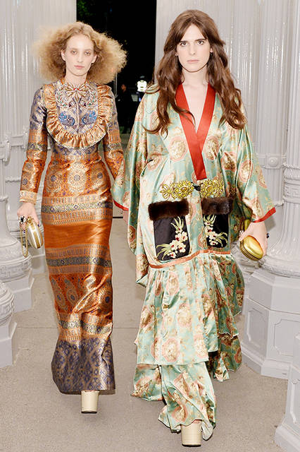 <strong>ペトラ・コリンズ</strong><br />ドレス：2017年クルーズ コレクション ルック68のピーコックの刺繍とラッフルディテールがあしらわれたゴールドジャカード ロングスリーブドレス<br />バッグ：メタリックシルバー クラッチ<br />シューズ：ヌードカラー プラットフォーム ウェッジサンダル<br /><br /><strong>ハリ・ネフ</strong><br />ドレス：2017年春夏コレクションのコントラストカラーのインサートとポケット、装飾が施されたトグルクロージャー、ブラックラムファーとブラウンミンクファーがあしらわれたグリーンシルク キモノコート<br />バッグ：クリスタル タイガーヘッド付きゴールド クラッチ<br />シューズ：ヌードカラー プラットフォーム ウェッジサンダル