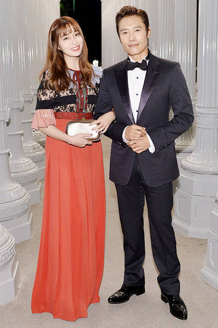 <strong>イ・ミンジョン</strong><br /> ドレス：2016年春夏コレクションのスパンコール刺繍のトロンプルイユカラー、スリーブとベルトがあしらわれたブラックレース レッドプリーツドレス<br /> バッグ：タイガーヘッドクロージャー付きメタリックレザー クラッチ<br /><br /> <strong>イ・ビョンホン</strong><br /> ウェア：ミッドナイトブルー ピークラペル ツーボタン シニョリーア タキシード、ホワイト イブニング シャツ、ブラック シルク ボウタイ<br /> シューズ：ブラック パテントレザー レースアップ シューズ