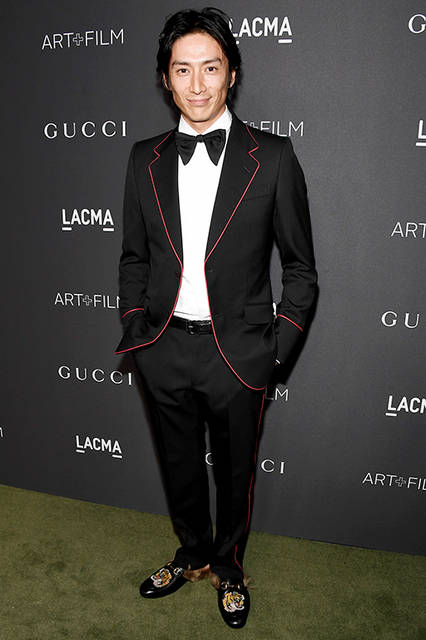 <strong>伊勢谷 友介</strong><br /> ウェア：2017年クルーズ コレクションよりルック52 のレッドトリム付き ブラック ツイル ノッチラペル ツーボタン ヘリテージ タキシード、ホワイト イブニング シャツ、ブラック シルク ボウタイ<br /> シューズ：タイガーヘッド パッチ、ファー付き スリッパ