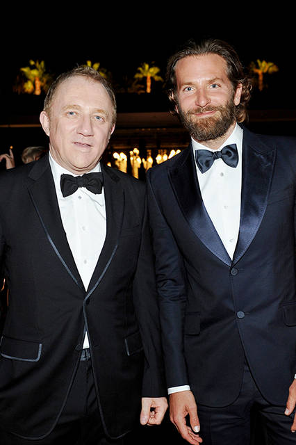 <strong>ブラッドリー・クーパー</strong><br /> ウェア：グッチ メイド・トゥ・オーダーのミッドナイトブルー ピークラペル ワンボタン マルセイユ タキシード、ホワイト ドレスシャツ、ネイビー サテン ボウタイ<br /> シューズ：ブラック パテントレザー レースアップ シューズ