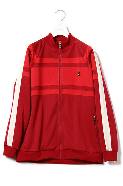 <strong>トラックスーツ</strong><br /> ポリエステルジャージ素材を使用したボリュームシルエットのスタンドカラーのジャケットと太目のストレートシルエットでリラックスムード漂うウエストゴムパンツの組み合わせ。）<br /> ベースカラーは渾身のレッドワンカラーのみで、ビンテージライクな色と質感を表現した。ジャケットに施されているトーンオントーンの切り替えは、テニスプレーヤーGuillermo Vilas（ギリェルモ・ビラス）のシグネチャーモデルに採用されていたラインをデザイン化したもの。）<br /> トラックスーツジャケット｜2万2000円（税別））<br /> トラックスーツパンツ｜1万4000円（税別））<br />