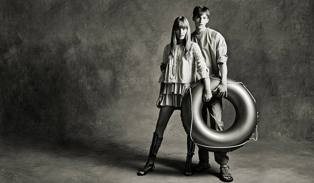 「メンズは、前身頃がシャツ地で後ろがジャージーになった異素材ミックスのプルオーバー。どことなく医師がオペ中に着ている術衣のよう。同系色のベージュのワークパンツにグラディエーターサンダルで軽やかに。ウィメンズはシャツ感覚で着られるスウェードのレースアップブルゾンに、ラッフルがあしらわれたミニスカート。こちらも足元はグラディエーターサンダルでリンクさせました」（左）レザージャケット15万5000円、レザースカート12万6000円、シューズ11万3000円（すべてディーゼル ブラック ゴールド）（右）プルオーバーシャツ2万8000円、パンツ3万6000円、サンダル6万8000円（すべてディーゼル ブラック ゴールド）