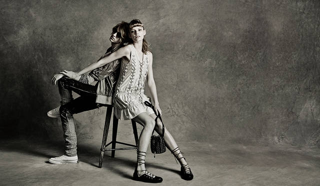 「堕天使的なミュージシャンに救いの手を差し伸べるグルーピーの物語。メンズはパンツの裾のくしゅくしゅ感に合わせてカットソーとブルゾンをレイヤード。タイトでありながらロング＆ルーズな着こなしに。ウィメンズはドレスとシューズ、バッグすべてにレースアップディテールで遊び心を」（左）ブルゾン4万8000円、デニムパンツ5万2000円（ともにディーゼル ブラック ゴールド）その他スタイリスト私物（右）ドレス7万5000円、バッグ8万6000円、シューズ3万9000円（すべてディーゼル ブラック ゴールド）