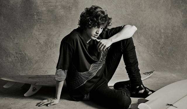 「70'sっぽいヘアスタイルが効いたラフなサーファースタイル。ゆったりした上半身に、ロング＆タイトなボトムスというディーゼル ブラック ゴールドらしいスタイリングにワンアクセント。一見シンプルなTシャツのレイヤードですが、下に着た7分袖のボーダーTがルーズなので、上に着たTシャツの柄が広がって面白い視覚効果が◎」Tシャツ1万3800円、ボーダーTシャツ1万6800円、デニムパンツ5万6000円、サンダル6万8000円（すべてディーゼル ブラック ゴールド）