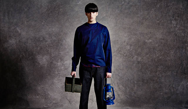 「キャンプ場の見回りバイト君です。ネイビーと赤のプリントTの上にプルオーバーをレイヤードして、一部ウェストイン。ボトムスはリジッドを選んで。着こなしが難しいといわれるネイビーのワントーンも、トーンを変えたり差し色を使ってアクセントをつけることで上級者の着こなしに」プルオーバーシャツ2万8000円、Tシャツ1万2800円、デニムパンツ2万7000円（すべてディーゼル ブラック ゴールド）