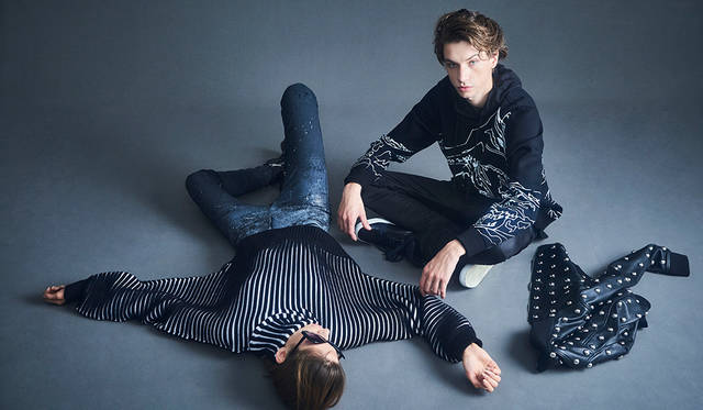 「ミュージシャンとグルーピーのような関係をイメージたスタイリング。ハンドドローイングされたような、どことなくロックテイストなグラフィックのスウェットパーカにデニムというスポーティなスタイルは、白ソールのスニーカーがアクセントに。ウィメンズは、ボリュームたっぷりのドルマンスリーブニットをメインにコーディネート。スキニーなペイントデニムとブーツでハードにまとめました」（左）ニット5万3000円、デニムパンツ4万9000円、ブーツ7万5000円、床に置いたジャケット24万5000円（以上ディーゼル ブラック ゴールド）その他スタイリスト私物（右）スウェット3万3000円、パーカ1万2800円、パンツ3万3000円、スニーカー5万4000円（すべてディーゼル ブラック ゴールド）