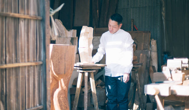 まっさらな木肌が眩しい、製作途中の作品を眺める矢崎さん。「リーバイス<sup>®</sup> メイド アンド クラフテッド™」（以下、LMC）の洗いざらしのシャツとも、シンクロしているように見える