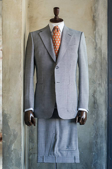 <strong>DUNHILL｜ダンヒル</strong><br><br>厚めの肩パッドとくびれたウエストで、英国ならではの色気のあるスーツスタイルを表現した一着。アイボリーの千鳥格子生地と脇下のパッチポケットによって、ほどよい落ち着きとリラックスした印象が醸し出されている。<br><br>ジャケット31万3200円、パンツ8万1000円、シャツ3万3480円、ネクタイ1万9440円／ダンヒル<阪急メンズ大阪3階・阪急メンズ東京3階>　※<オーダーフェア>阪急メンズ大阪：2月15日(日)〜3月31日(火)。4月18日(土)、19日(日)にスペシャリストが来店。阪急メンズ東京：2月15日(日)〜3月31日(火)。2月28日(土)、3月1日(日)にスペシャリストが来店。