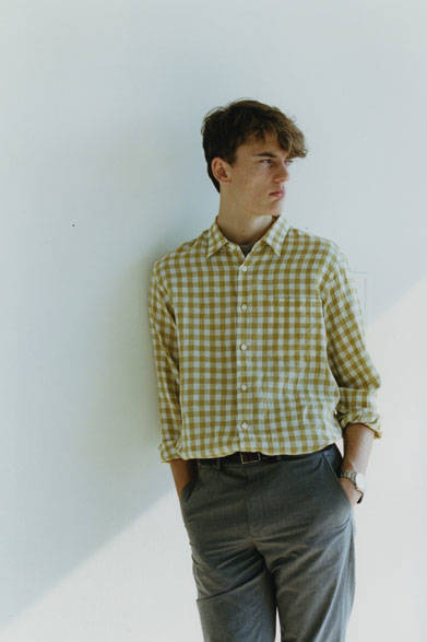 <strong>MARGARET HOWELL｜マーガレット・ハウエル</strong><br />今シーズンのキーカラーであるイエロー（メイズ）をリネンシャツで表現。やや大きめのギンガムチェックの落ち着いた色味は、カジュアルすぎずデイリーに着こなせるのが魅力だ。シャツ 3万5640円、Tシャツ 1万800円、トラウザーズ 3万1320円、ベルト3万7800円、時計3万9960円（すべてマーガレット・ハウエル）