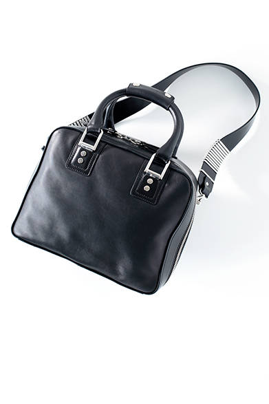 <strong>WOMENS｜</strong>薄着になるこれからの季節、コンパクトな着こなしにボリュームのあるバッグを合わせてバランスを取るのがスタイリストのふくしま流。レザーの質感とメタルパーツのコントラストが目を引くソリッドなデザインは、スタイリングにモードなアクセントをくわえてくれる。[W28×H22×D13cm]バッグ11万160円（ディーゼル ブラック ゴールド）