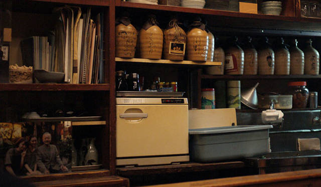 <strong>角田陽太｜「東京浪漫酒場」｜第八回 恵比寿「さいき」</strong><br />カウンター内はまるで田舎の祖父母の家のような感じ。店主の写真も飾られている