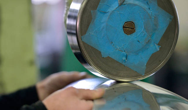 アルミ板をローラーのあいだで圧延してボディパネルをつくる