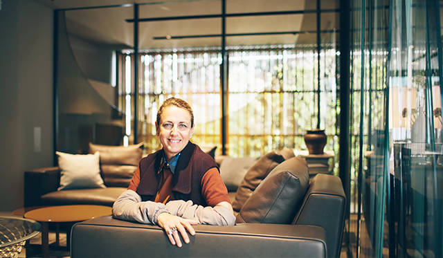 Patricia smiling to the camera with 'wooden wall' on her back.