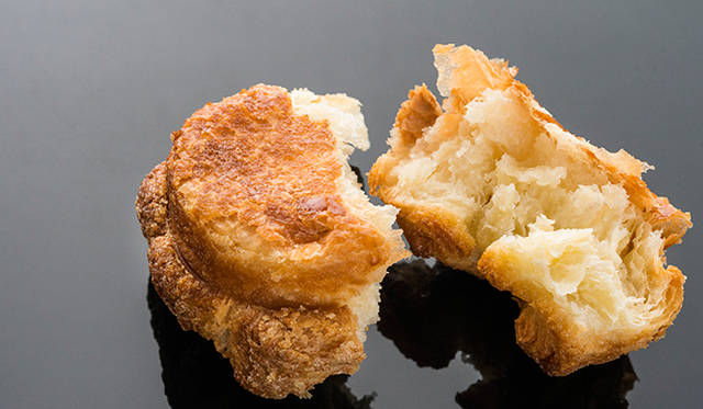 「DKA（ディーケーエー）」<br>ドミニク・クイニーアマンを意味する「ディーケーエー」は、フランスブルターニュ地方の伝統菓子「クイニーアマン」をベースに、ドミニク氏がオリジナルでレシピを開発。バターをたっぷり使ったリッチな風味のペイストリー生地を焼きあげて表面をキャラメライズ。カリッと香ばしく濃厚な味わいながらも甘さ控えめで、完璧なバランスに仕上げている。